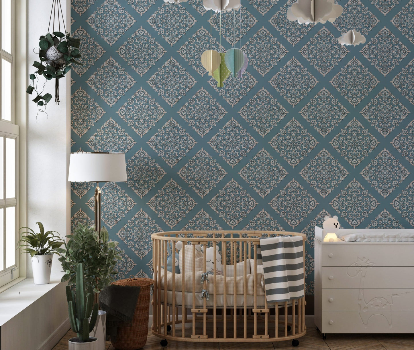 Blue damask wallpaper in nursery behind wooden crib and dresser.