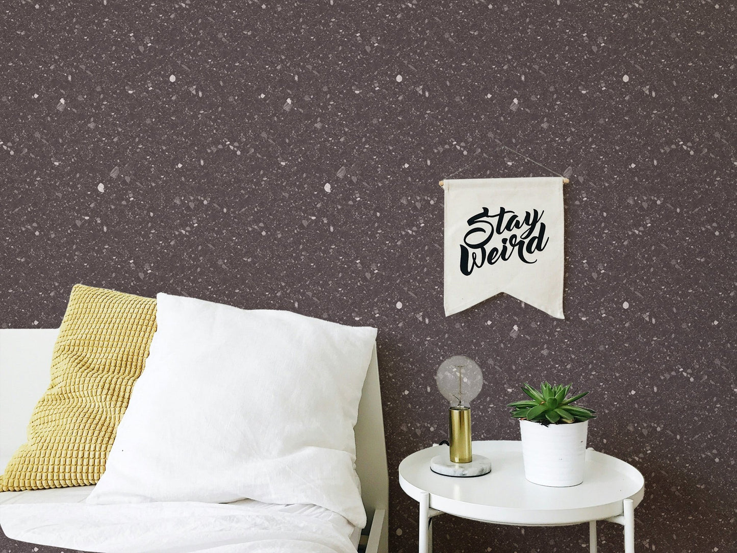 Dark brown speckled wallpaper in a bedroom corner with a white round side table.