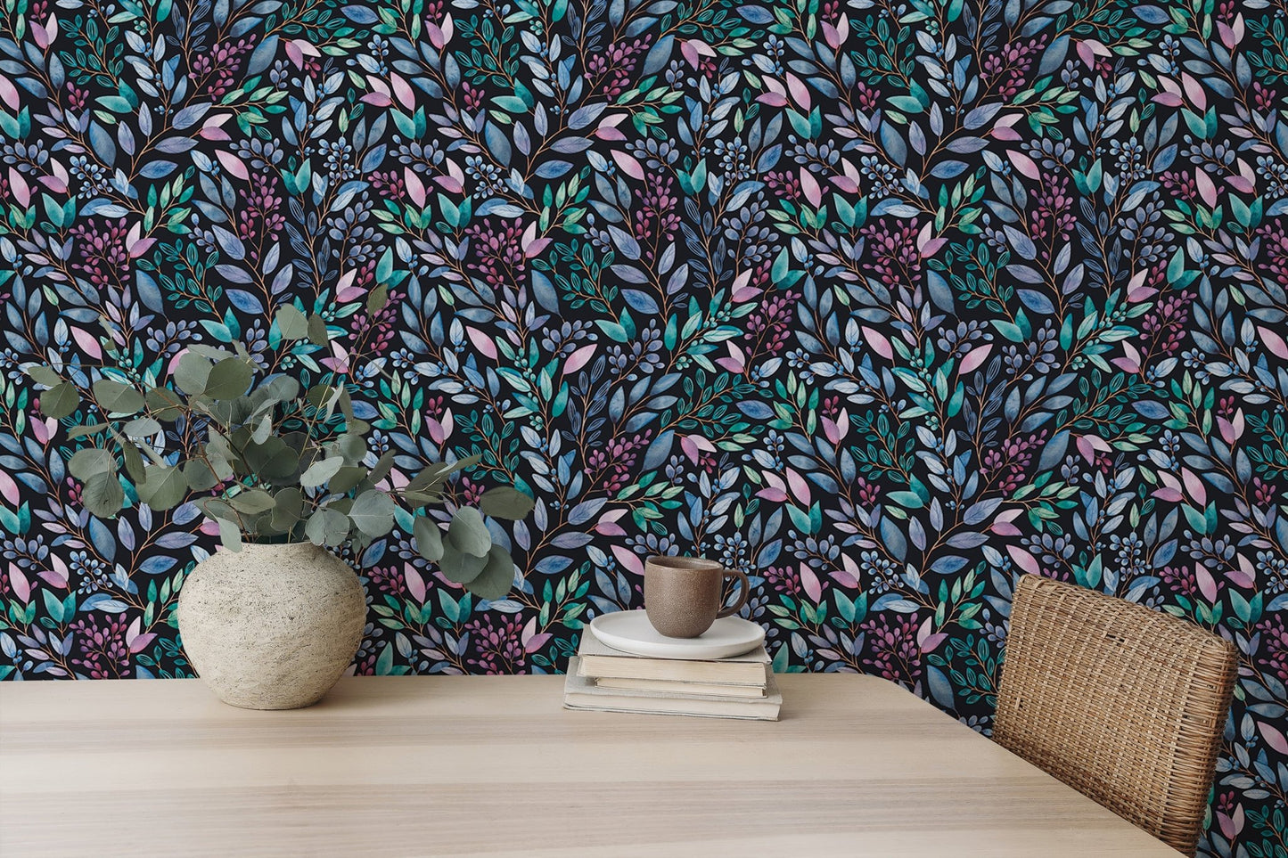 Hand painted leaves wallpaper behind a light wood desk and potted plant.