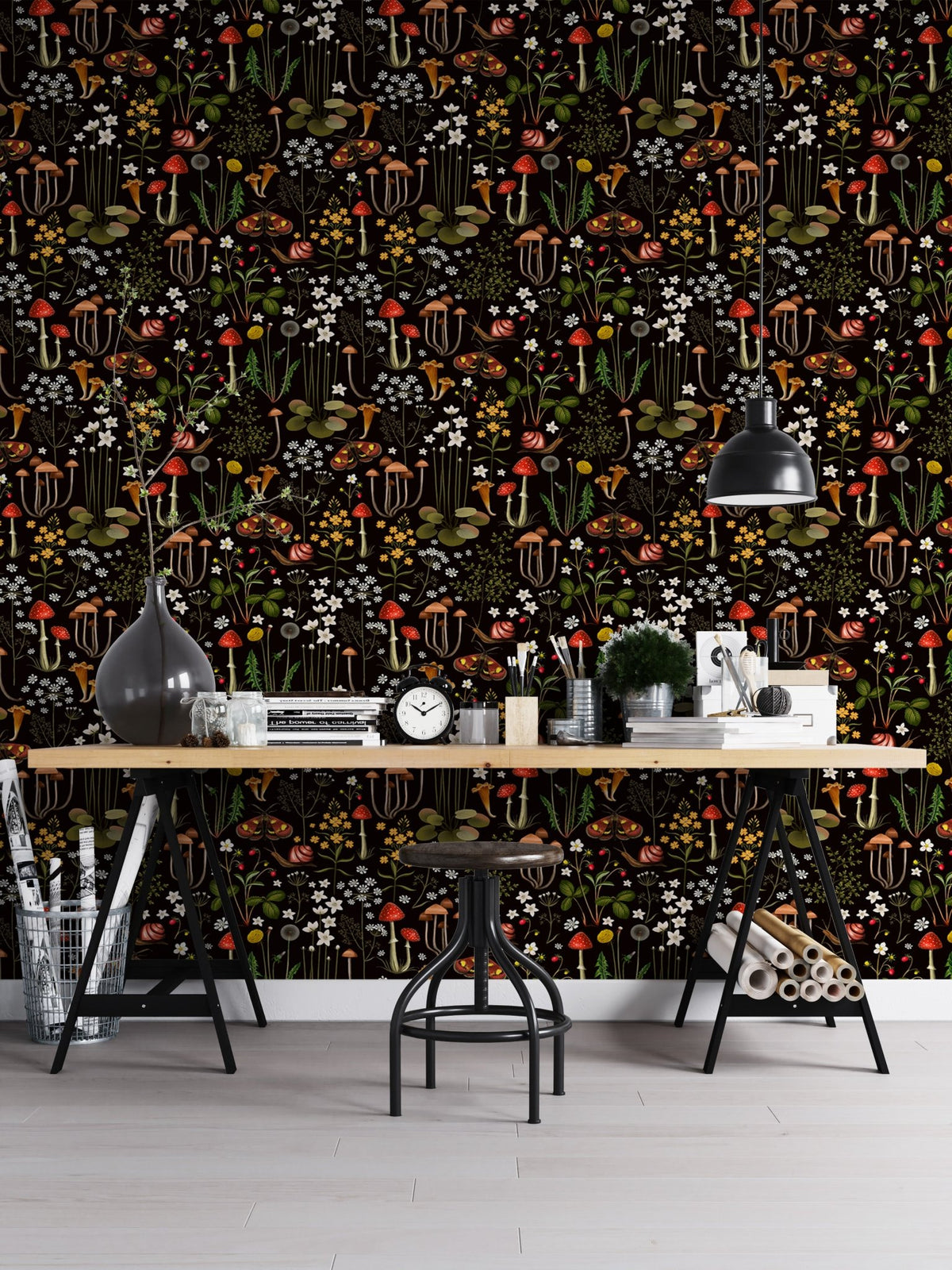 Home office setup with a long wooden desk and dark forest pattern wallpaper.