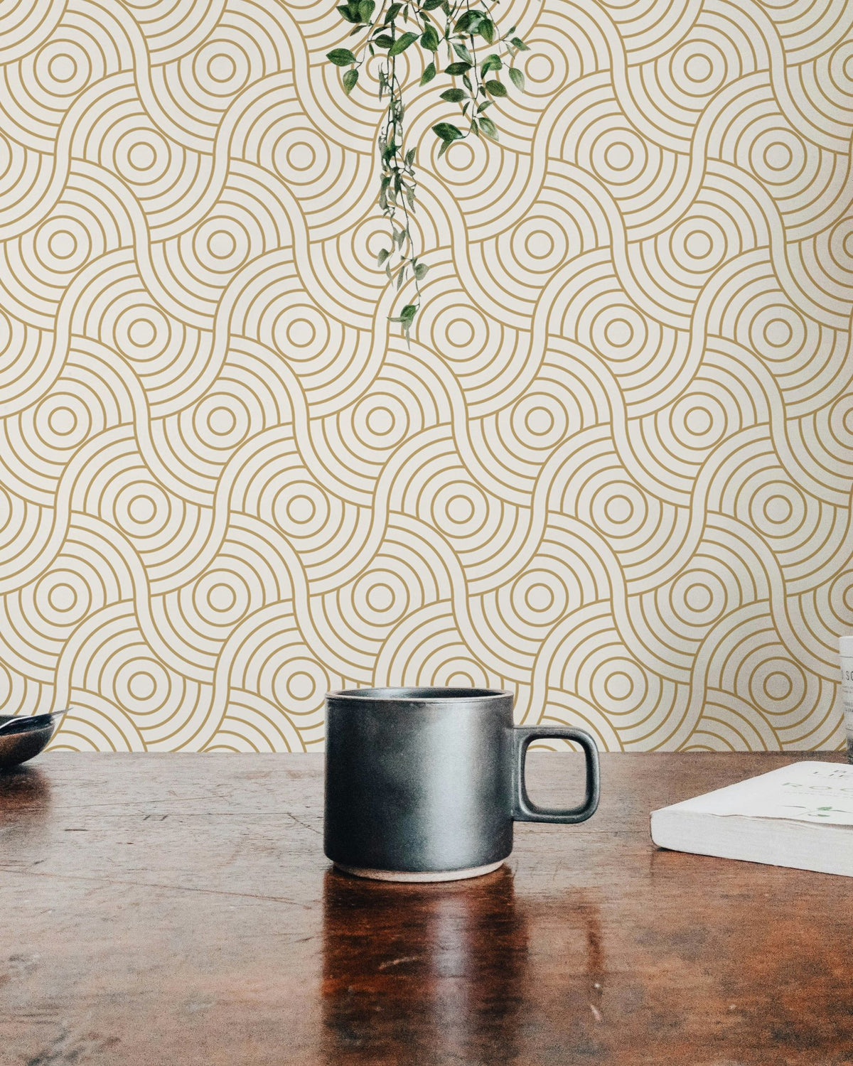 Workspace view with a black mug and gold abstract circle wallpaper backdrop.