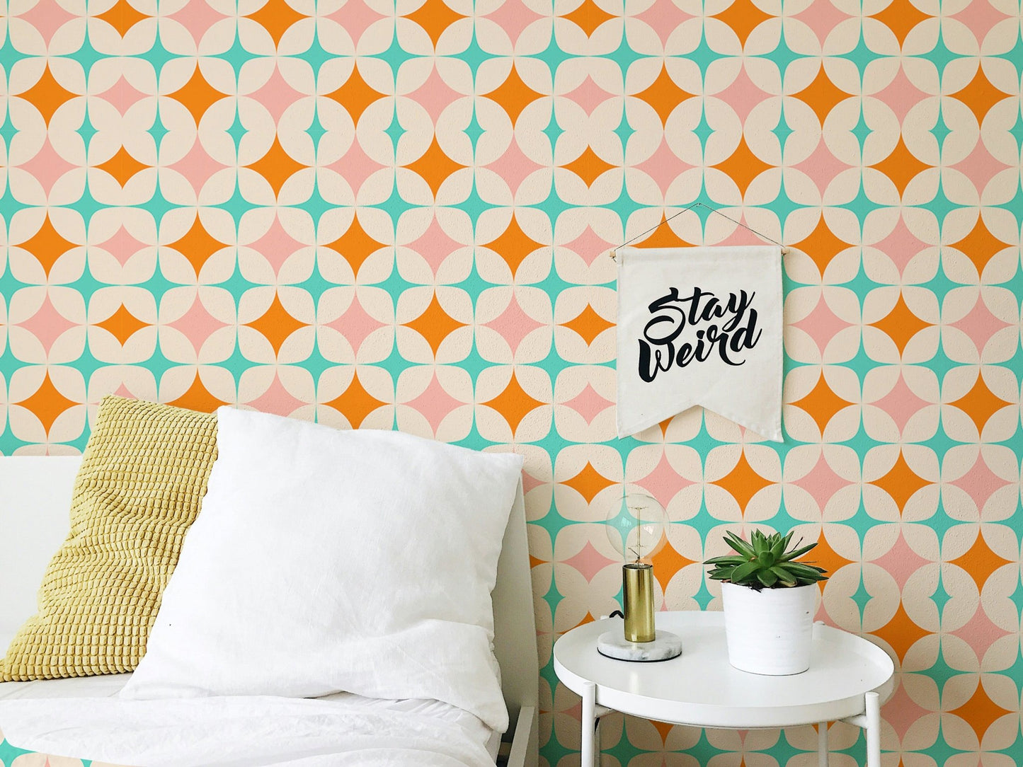 Geometric star wall mural in bedroom behind bed and white table.