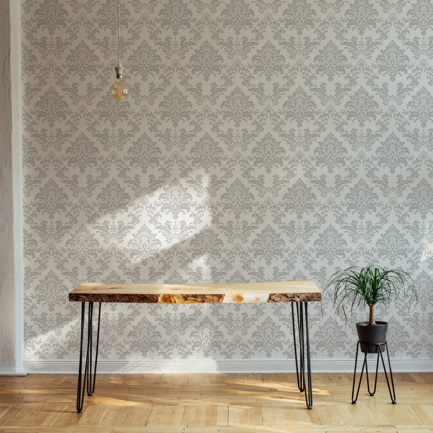 Repeat pattern damask wallpaper in a minimalist room with a thin wooden desk.