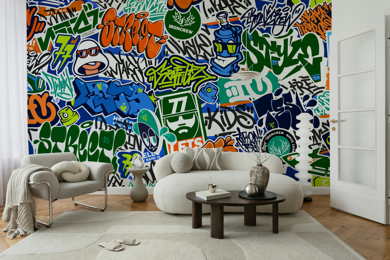 A wall mural featuring a bold, layered design of urban graffiti and stickers.

