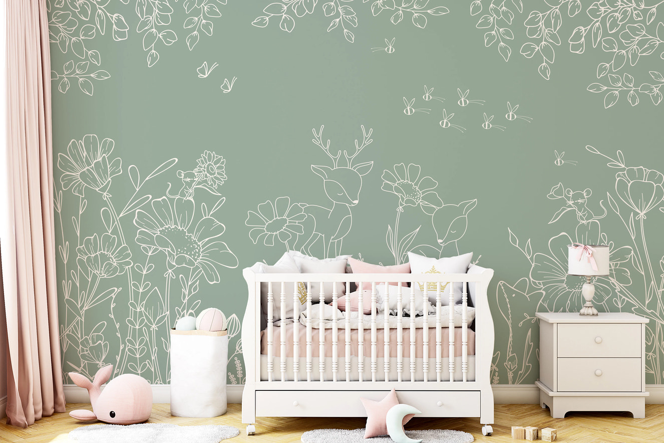 Sage green wall mural with white deer doodles in a nursery with a white crib.