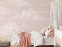 Pastel pink cloud wall mural in child's bedroom with soft white cloud motif. 