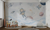 Cute astronauts floating alongside rockets, planets, and clouds in outer space.