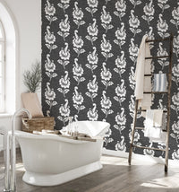 Black damask wallpaper in a bathroom with a white freestanding tub.