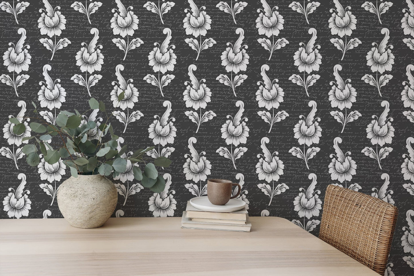 Black and white leaf wallpaper behind a light wood desk with a potted plant.