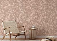Textured beige brush dots wallpaper  behind chair in reading area.
