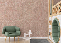 Green armchair and rocking horse in front of beige wallpaper.



