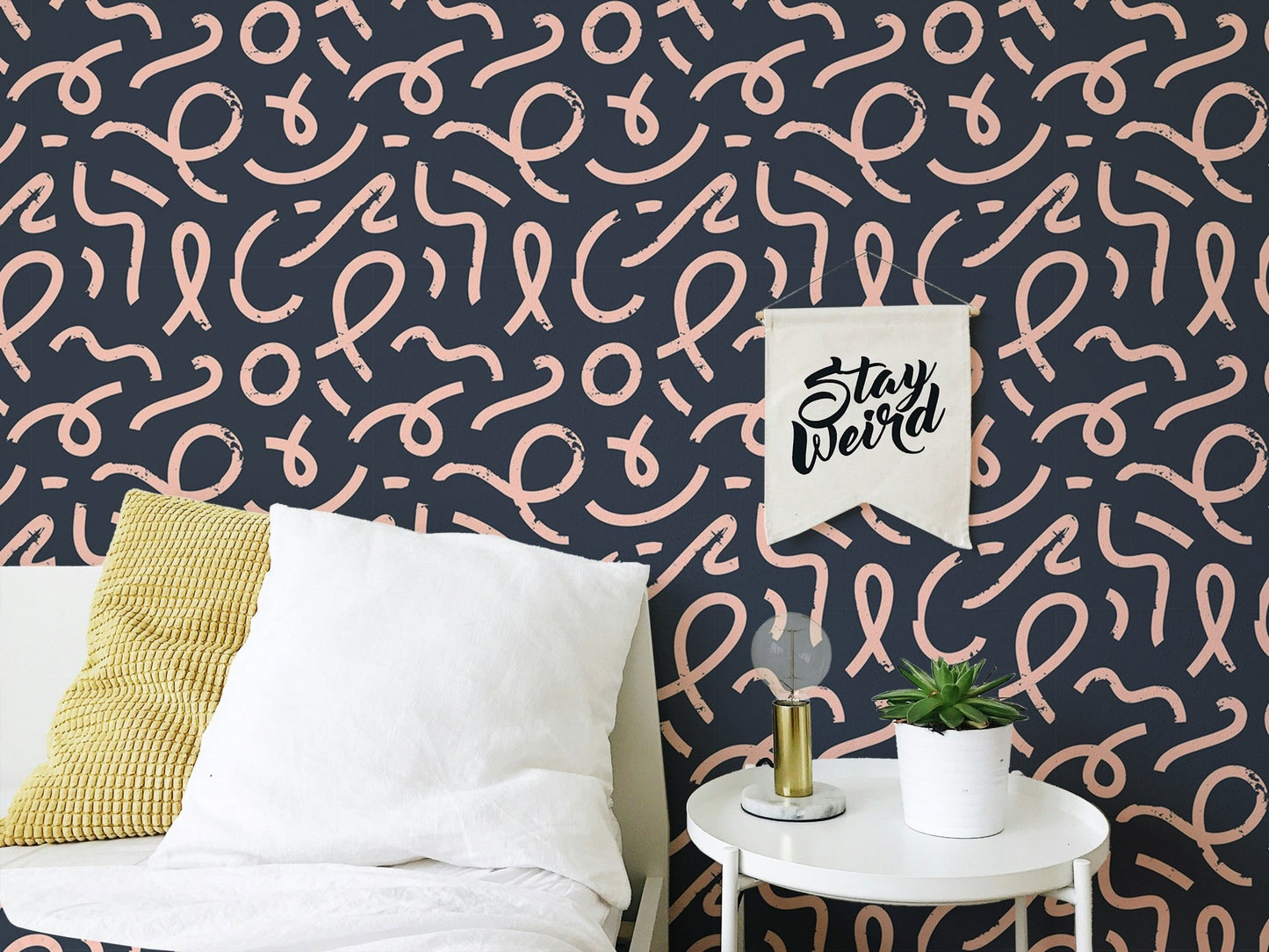 Abstract minimal line brush stroke wallpaper behind a white bed with yellow pillow.