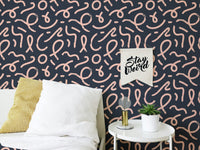 Abstract minimal line brush stroke wallpaper behind a white bed with yellow pillow.