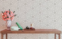 Geometric line wallpaper behind a wooden console table with flowers.