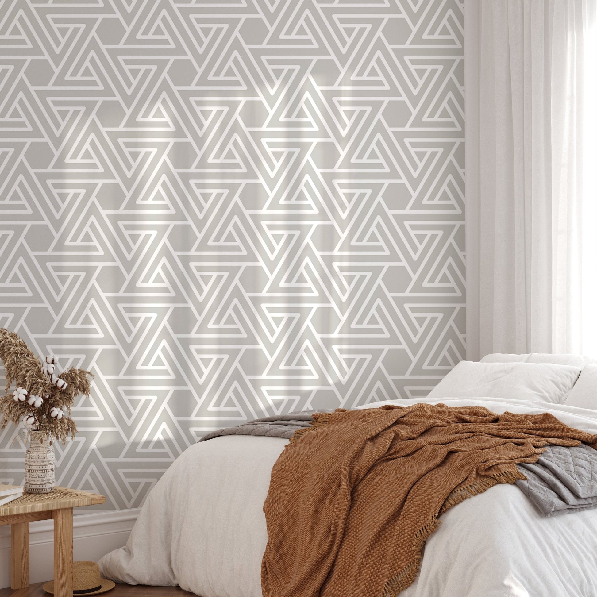 Geometric triangle wallpaper behind a white bed with brown bedding.