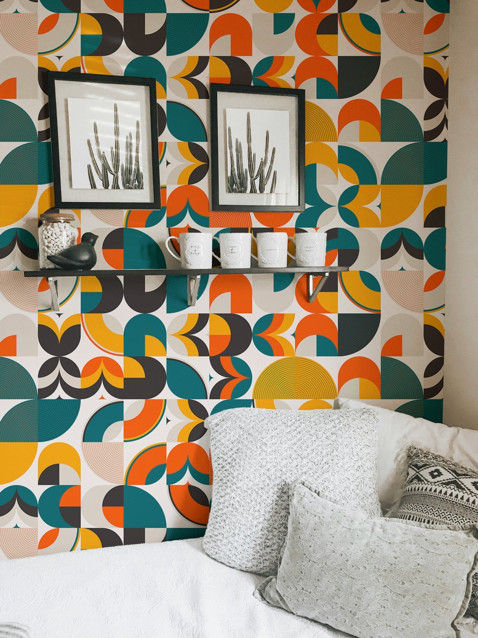 Scandi art wallpaper in a bedroom area with grey cushions and black frames.