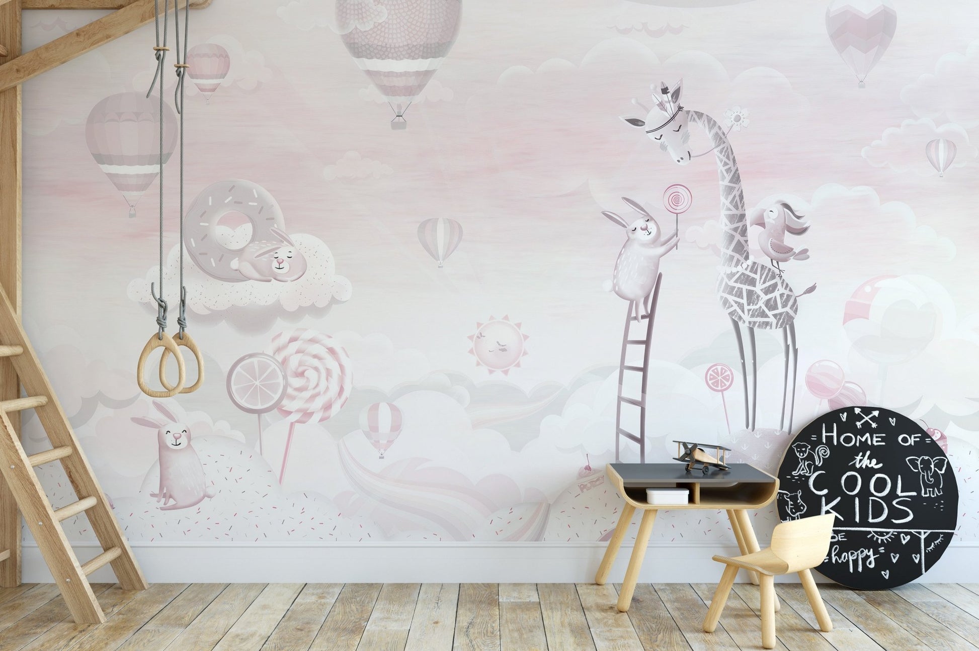 Gym rings in a playroom with light pink cartoon wall mural illustrations.