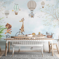 Animals in hot air balloons wall mural behind a wooden dining table and chairs.