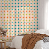 Sunlit bedroom featuring a repeating star pattern wall mural and white linen.