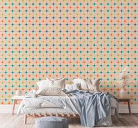 Bedroom wall mural with orange and teal vintage stars behind a bed with grey cushions.