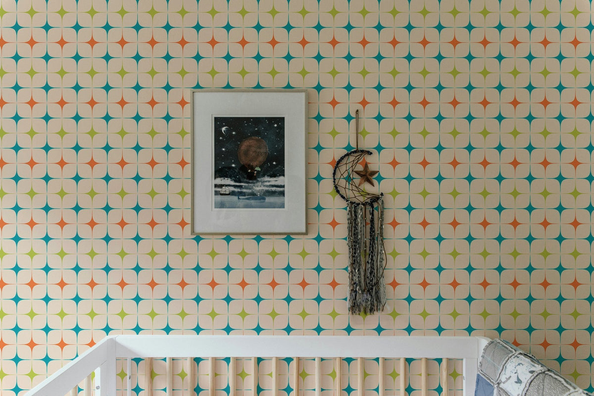 Geometric star pattern wall mural in a nursery with a white cot and framed art.