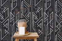 Wooden stool and vase against dark geometric wallpaper in a minimalist room.