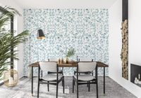 Dining room with aqua leaf print wallpaper on the main wall.