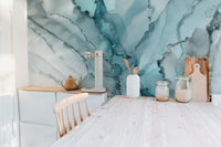 Light teal ink flow wall mural in a bright kitchen with white wooden furniture.