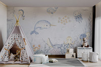 Light blue narwhal with golden horn aquatic animals wall mural in playroom.