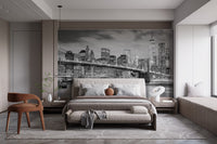 Grey scale city bridge wall mural in a spacious bedroom with a neutral bed frame.