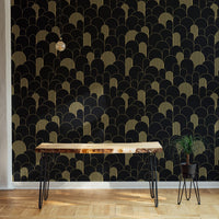 Symmetrical gold line wallpaper behind a dark wood table and desk lamp.