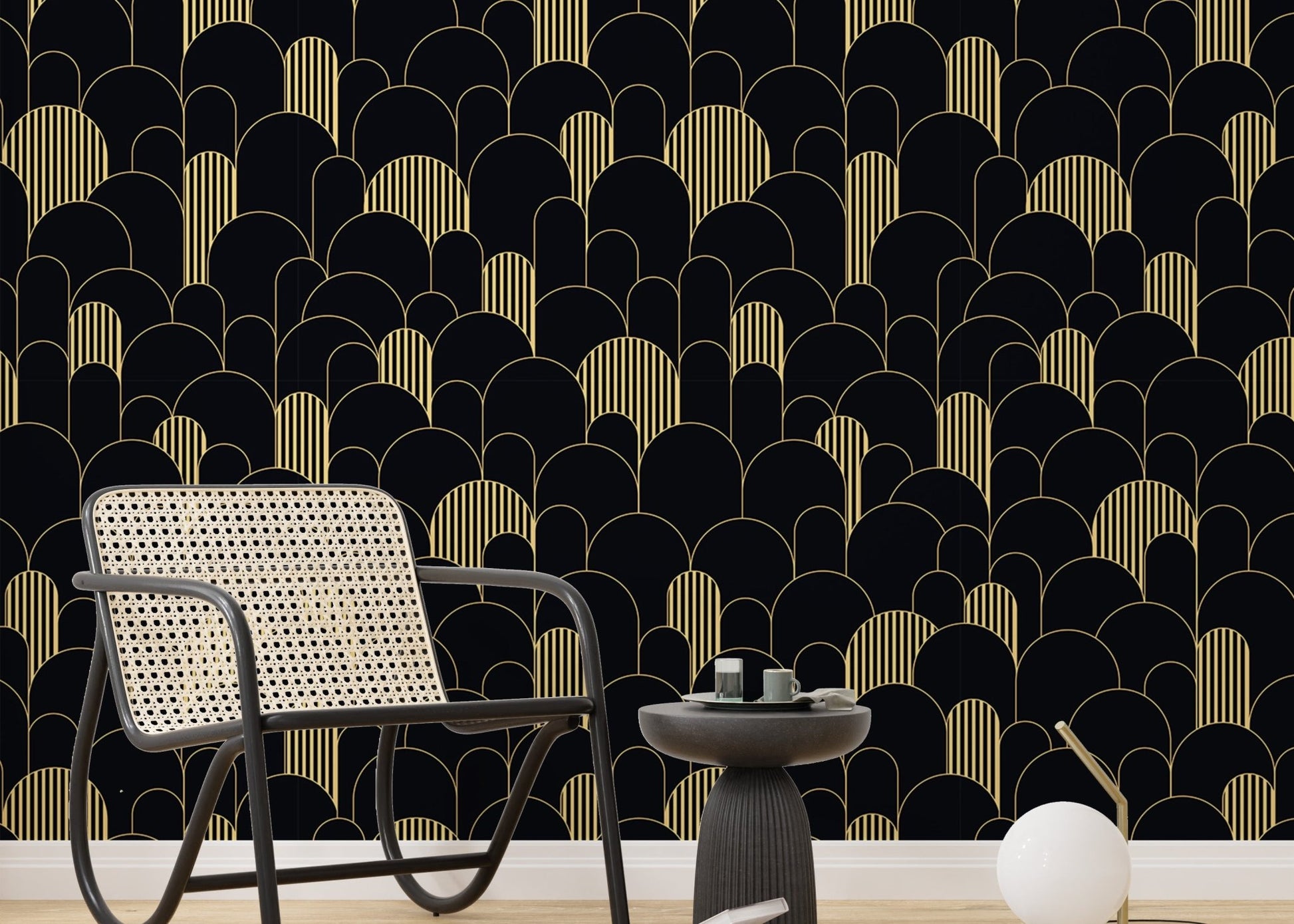 Black and gold Art Deco wallpaper in a sitting room with a grey chair and side table.