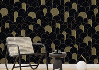 Black and gold Art Deco wallpaper in a sitting room with a grey chair and side table.
