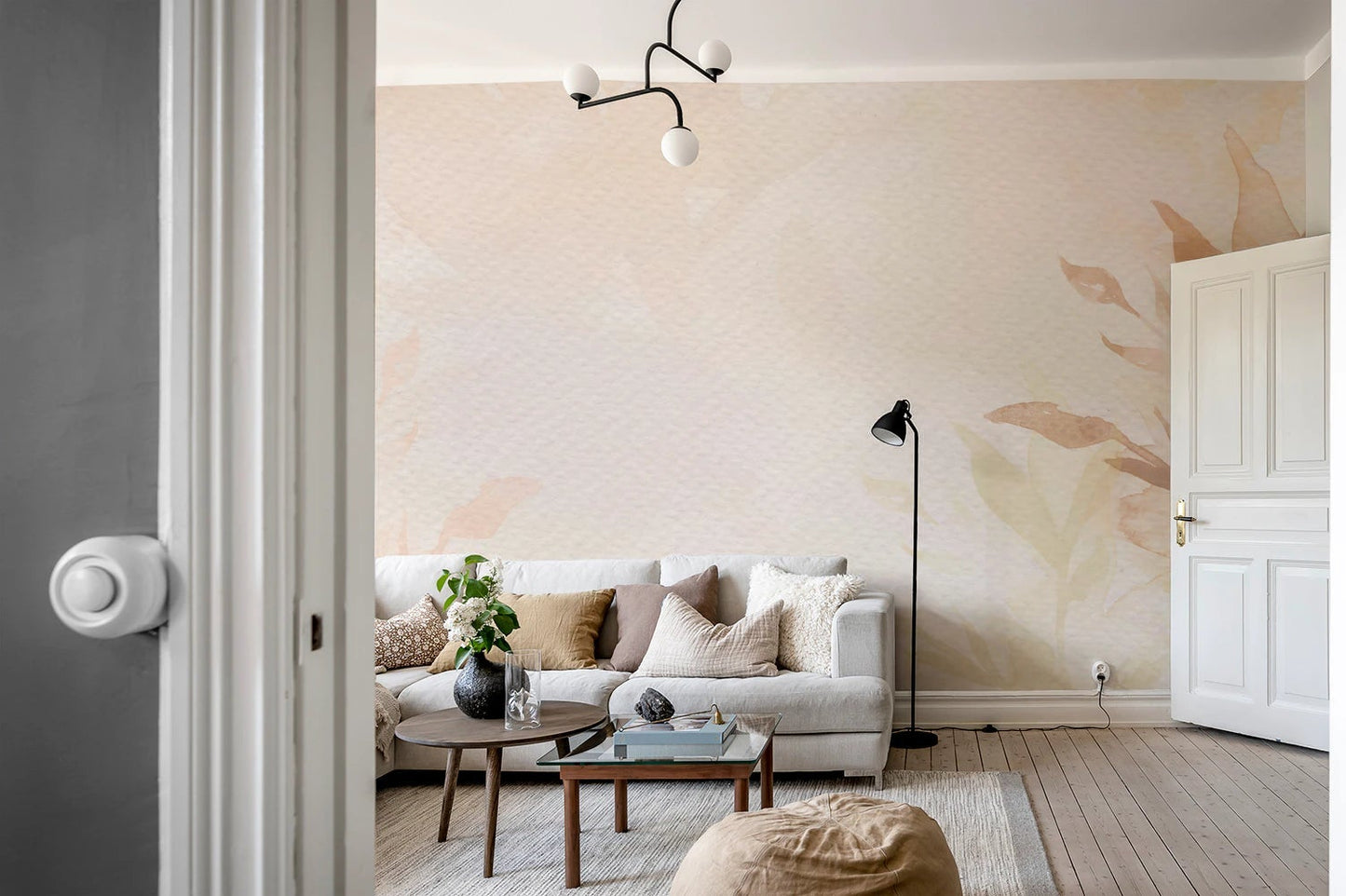 Blurred doorway view of a sitting room with blush leaf wall mural.