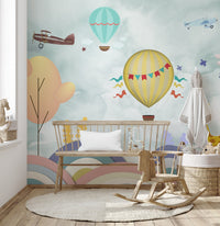Wooden rocking horse on a round rug near a cartoon sky wall mural.