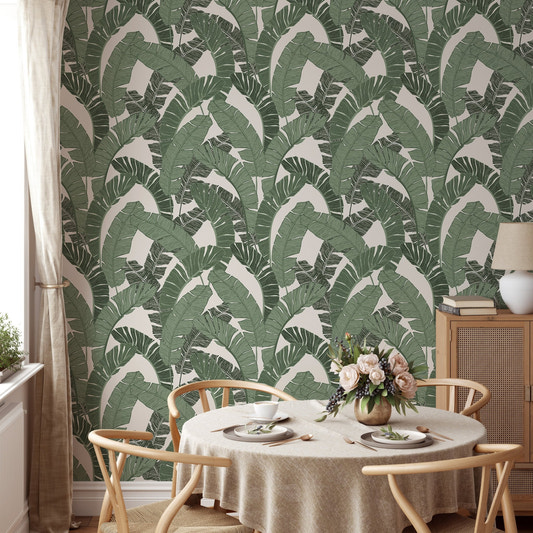 Green banana leaf wallpaper in a dining room with a round wooden table.