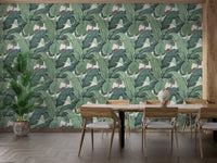 Green tropical leaf wall mural in a dining area with wooden furniture.
