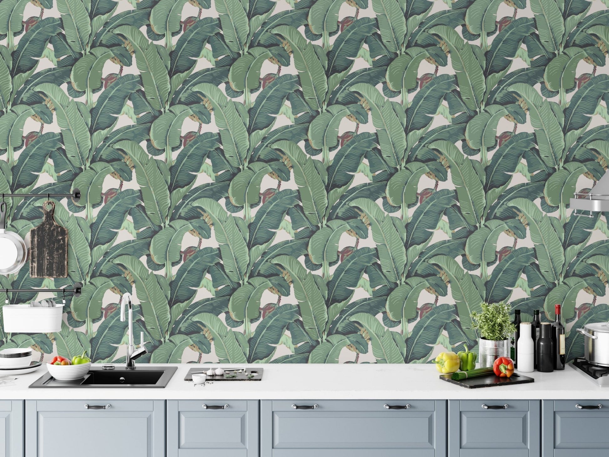 Tropical greenery wall mural used as a kitchen backsplash behind white counters.