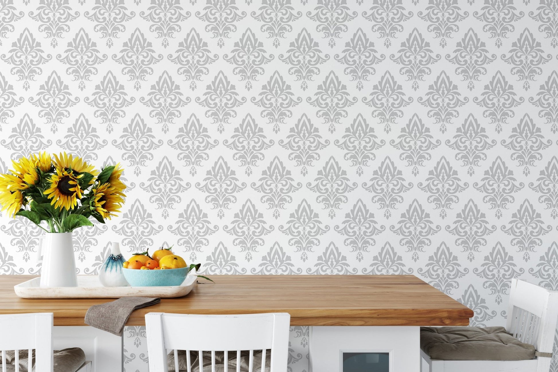 Gray and white damask wallpaper in a dining area with a wooden table.