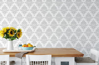 Gray and white damask wallpaper in a dining area with a wooden table.