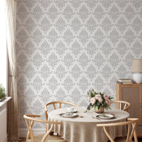 Symmetrical damask wallpaper on the wall of a round dining table setup.