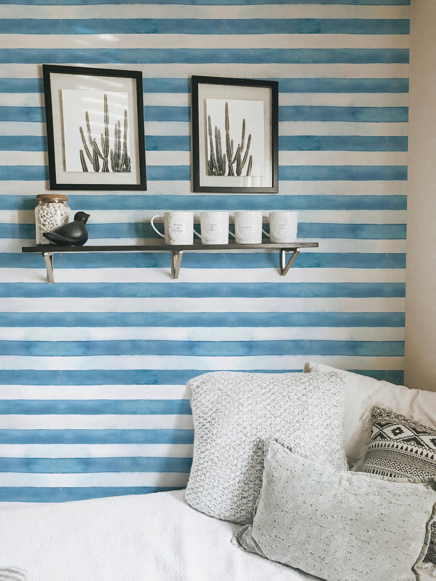 Wall shelf and pillows against blue and white striped wallpaper.