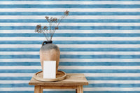 Small wooden table and vase near horizontal blue stripe wallpaper.