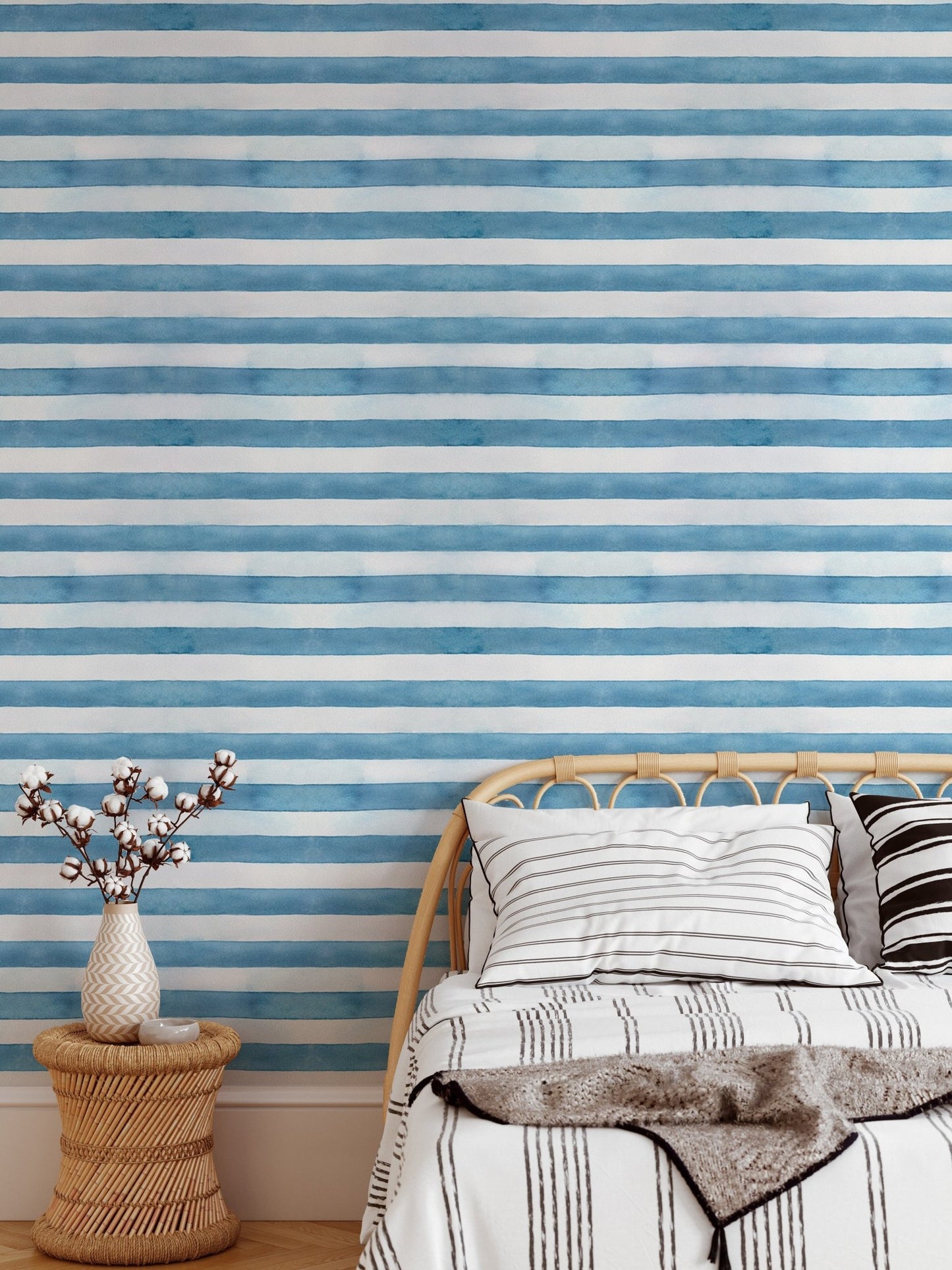 Single bed with blue and white watercolor stripe wallpaper backdrop.