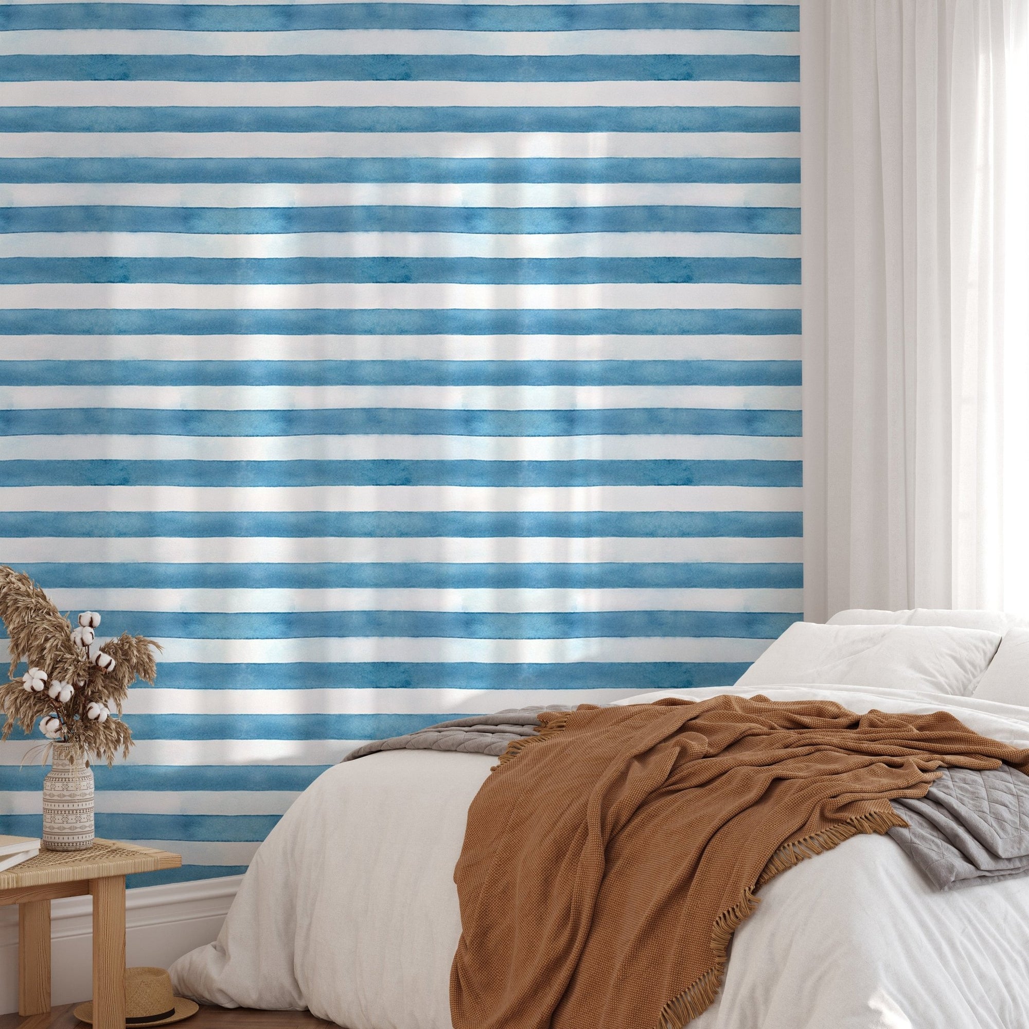 Bedroom with blue and white watercolor stripe wallpaper and brown throw.
