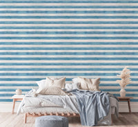 Double bed with textured blue stripe wallpaper and side tables.