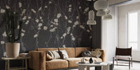 Minimalist seating area with black botanical wall mural and leather sofa.