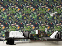 Dark green tropical pattern wall mural behind a black leather sofa in a living room.