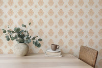 Light beige damask wallpaper behind a desk with a vase of eucalyptus leaves.
