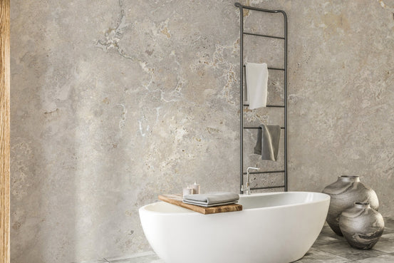 Beige marble wall mural accentuating a white soaking tub and grey tiled floor.